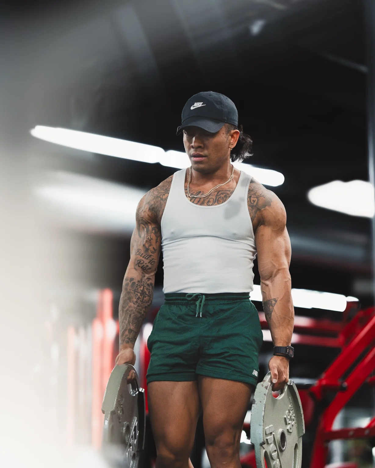 Aries Ballena, Head Coach, Founder and Owner of AZ BUILT Athletics, carrying weight plates in the gym